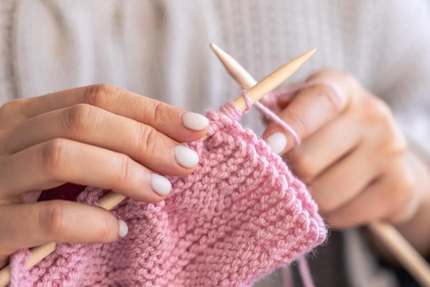 Nahaufnahme von Händen, die mit Rundstricknadeln stricken.