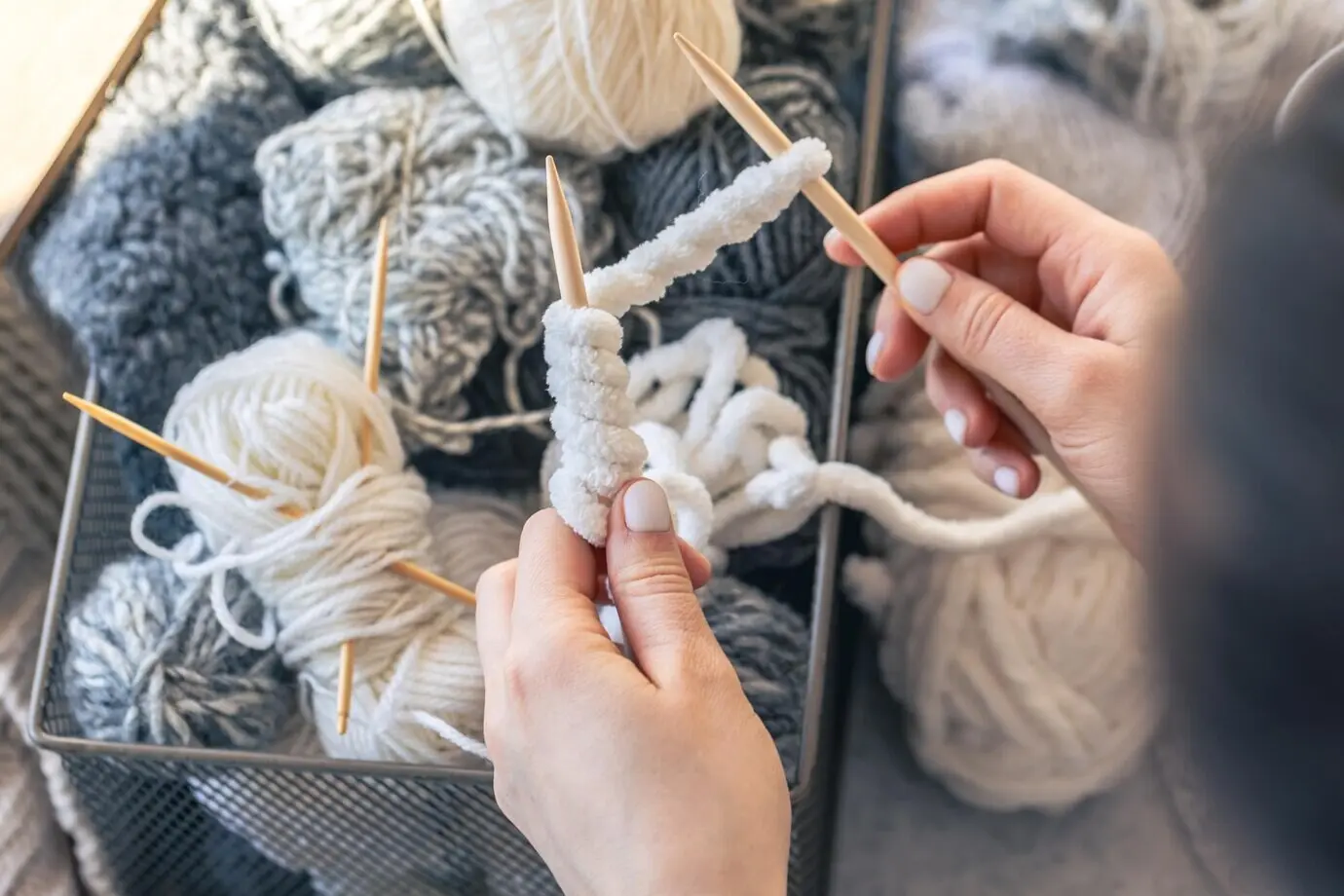 Nahaufnahme weiblicher Hände beim Stricken eines Wollpullovers, Ansicht von oben